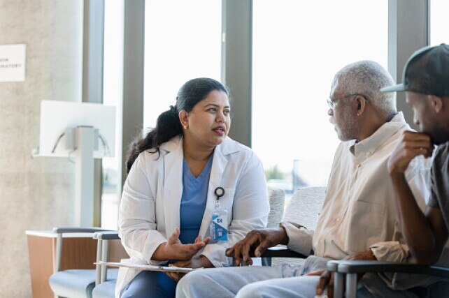 Female doctor talking with senior male patient and his son