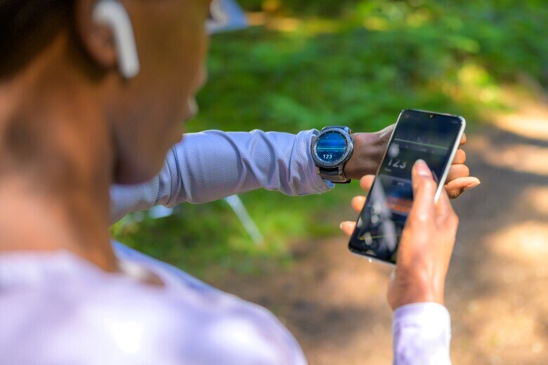 woman connecting her smartwatch with her mobile phone
