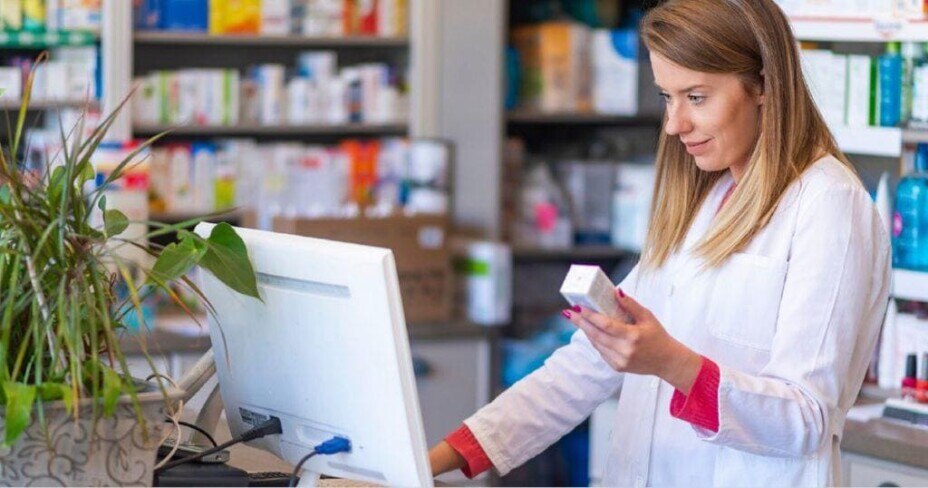 Pharmacist using a computer to check the details of a prescription medication