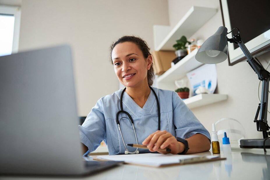 Doctor sitting at her desk and looking at a laptop