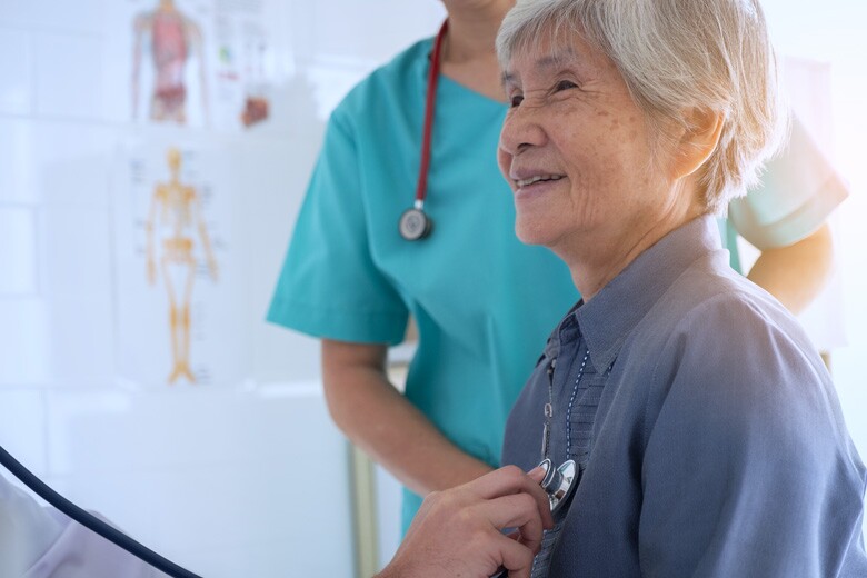 doctor listening with a stethoscope to the heart of a senior patient