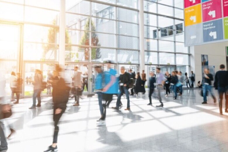 crowd of people moving fast through a modern lobby area