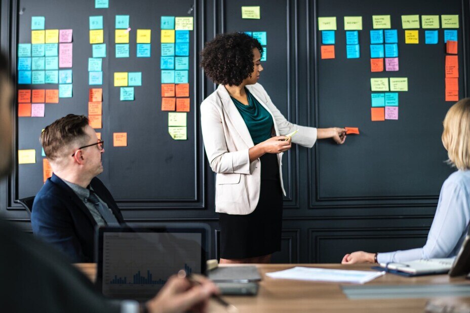 woman leads a business meeting in a brainstorming exercise using sticky notes