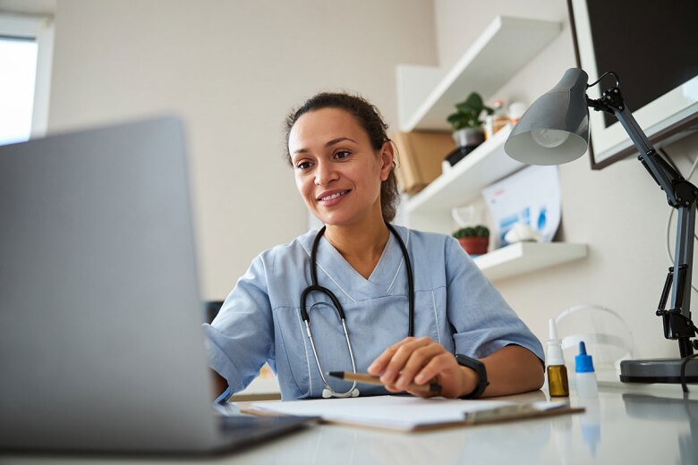 Doctor sitting at her desk and looking at a laptop