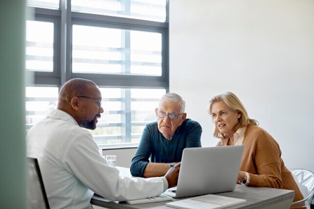 Male doctor showing senior couple how to use online patient portal