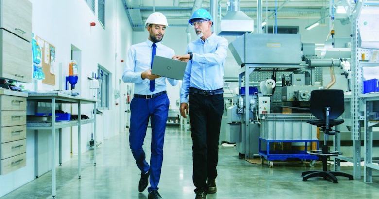 colleagues wearing hard hats walking through factory