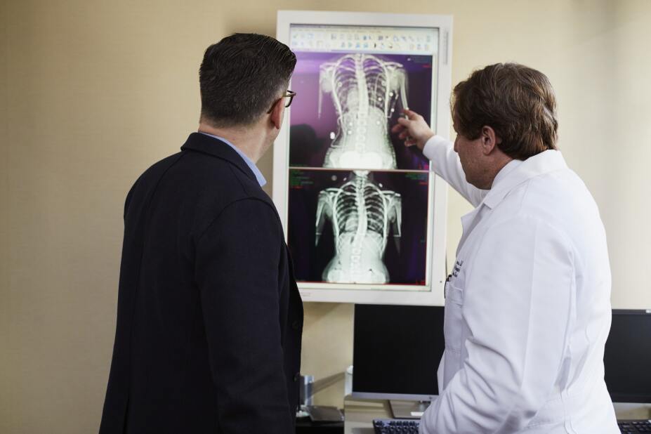 a doctor reviews two x-rays of a chest cavity with a patient