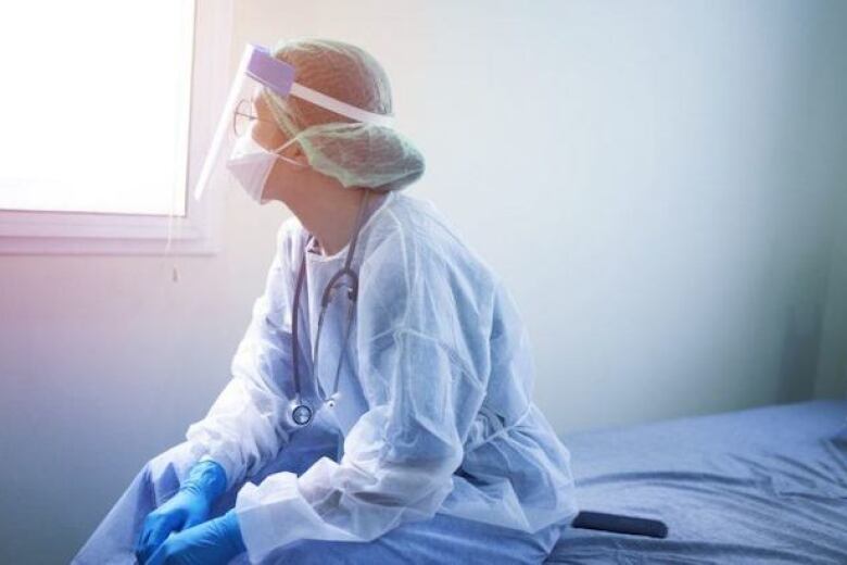 female doctor in protective gear taking a break in a hospital
