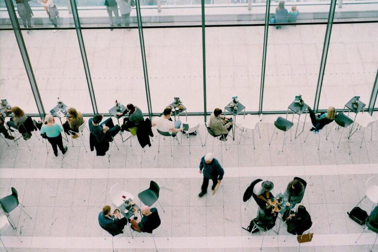 people sitting at small tables with food in a large room