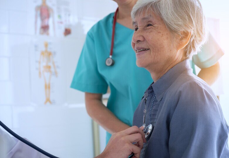 doctor listening with a stethoscope to the heart of a senior patient