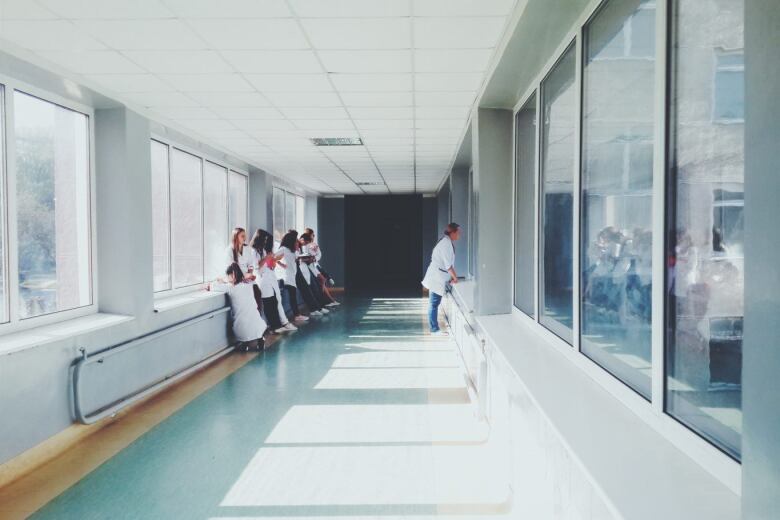 group of doctors watch and listen to another doctor in a hospital hallway