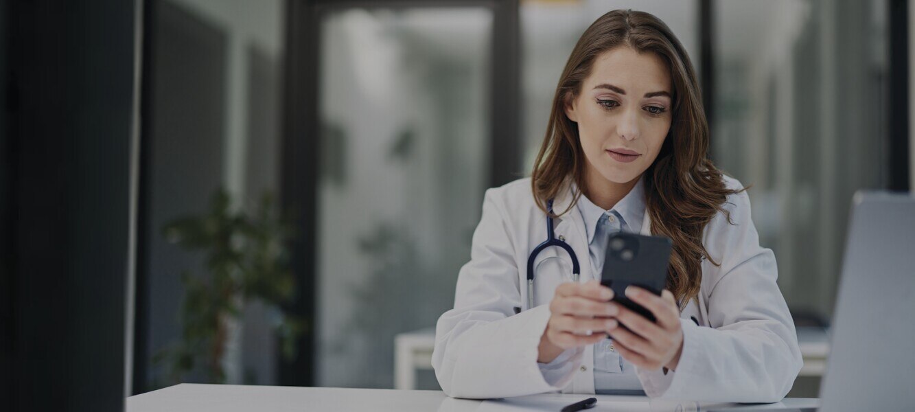 A female doctor using a mobile phone while sitting at her desk