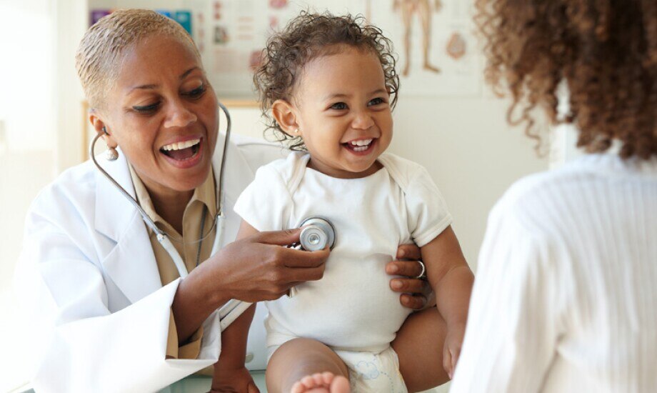 doctor listening to the heart of a smiling toddler patient