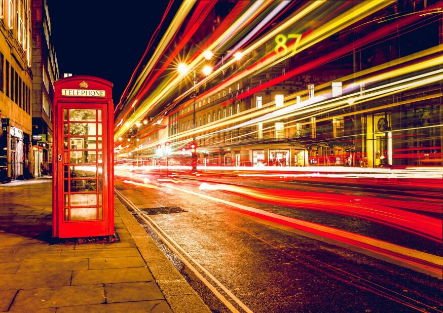 A busy London street at night with blurred, streaks of light from the passing cars
