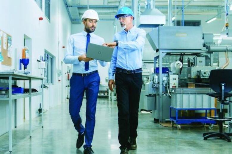 colleagues wearing hard hats walking through factory
