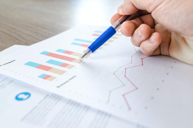 hand holding pen while reviewing printouts of data graphs