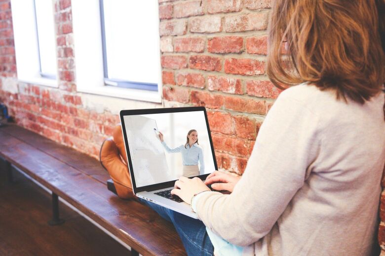 woman watching a presenter speak during a webinar on her laptop
