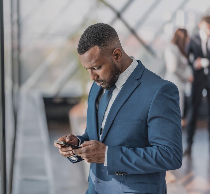 Businessperson standing by the window looking at his mobile phone