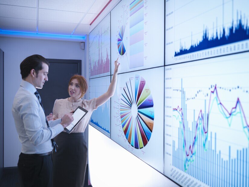 Business colleagues discussing graphs on screen in meeting room