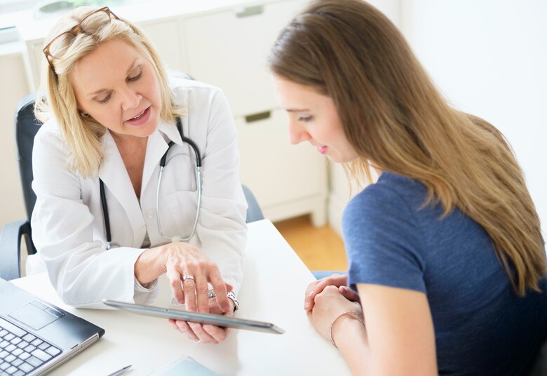 doctor looking at information on a tablet with young female patient