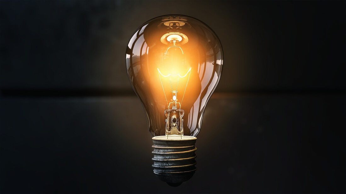 clear lightbulb glowing orange over a dark gray background