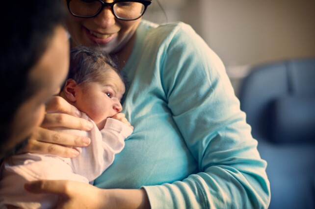 woman holding a newborn baby close to her chest