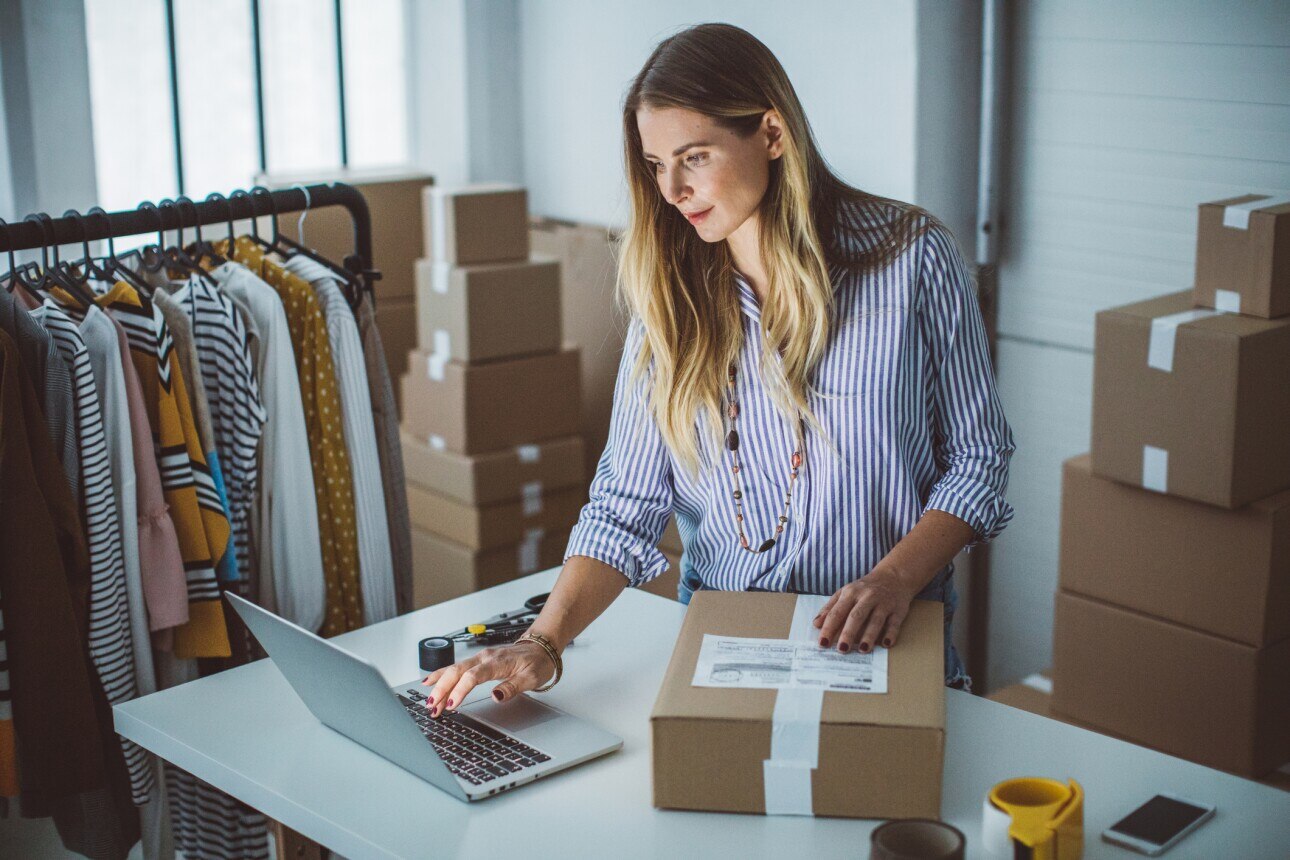 Women, owner of small business packing product in boxes, preparing it for delivery.