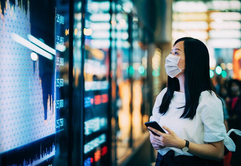lady wearing a mask looking at financial data on a screen