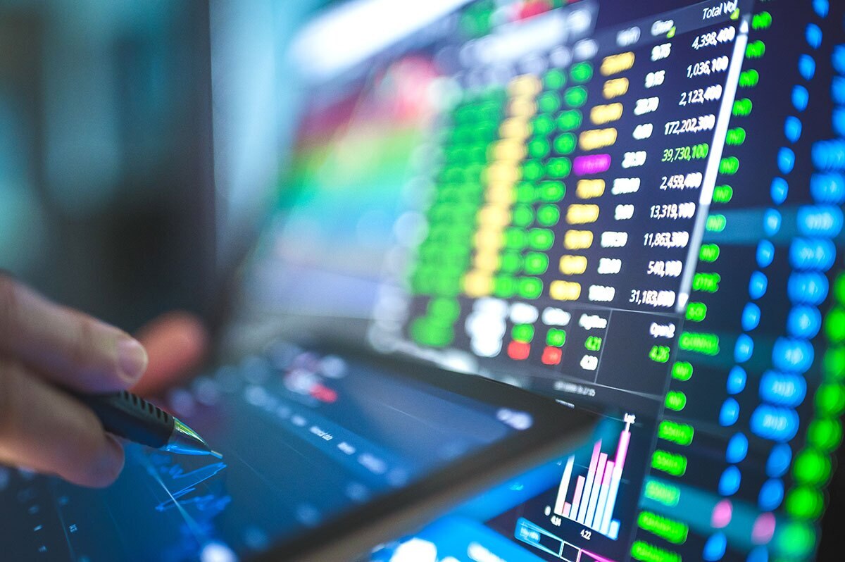 person reviewing tock market or financial data on computer screen and tablet