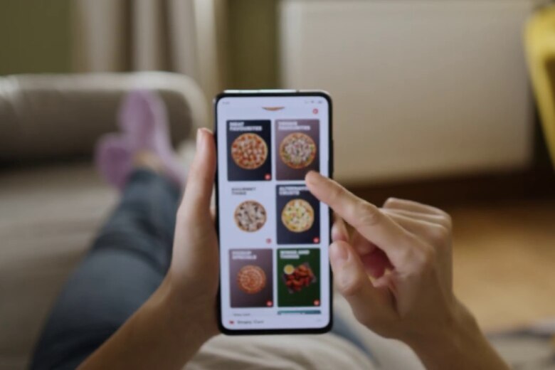 woman's hand ordering a pizza from her mobile phone