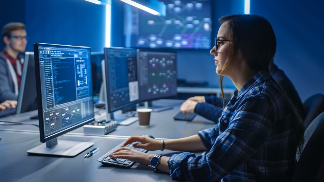 Software developer working on a computer, sharing space with other developers