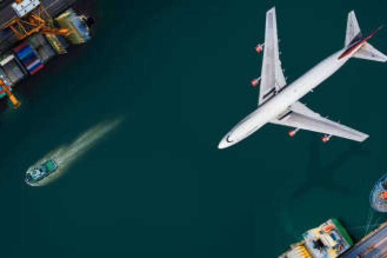 Aerial view and top view cargo plane flying above ship port in the export and import business and logistics international goods. Shipping cargo to harbor by crane