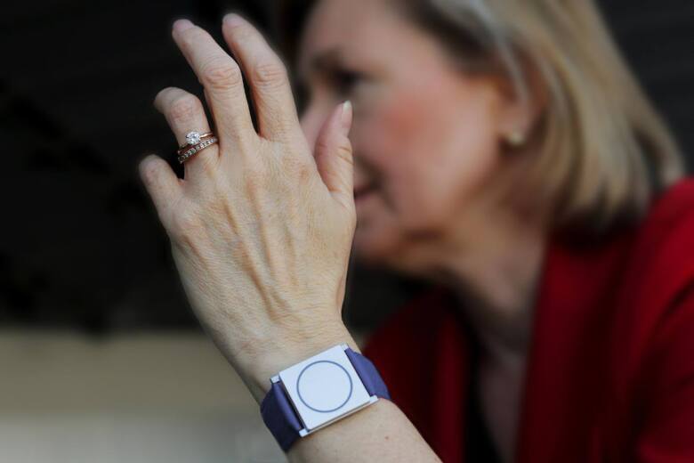 women's hand wearing wedding rings and a smart watch