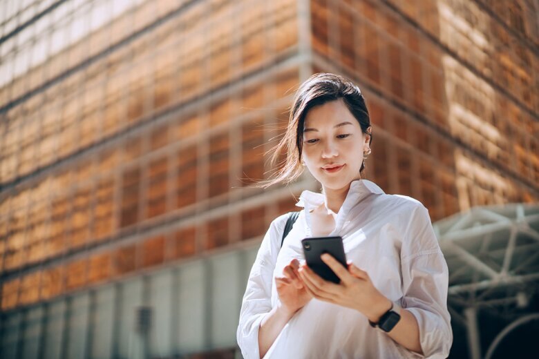 young woman outside looking at her phone in an urban setting