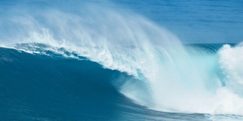 Large wave breaking out at sea, creating white surf
