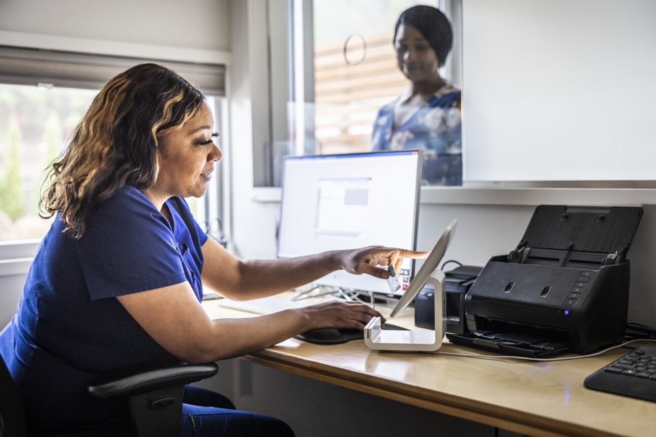Female nurse accepting payment from patient at reception desk in doctor's office