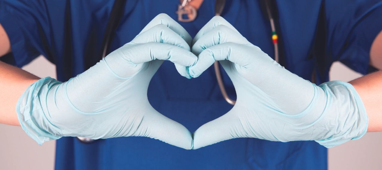 A doctor or nurse shpwing a heart with their hands