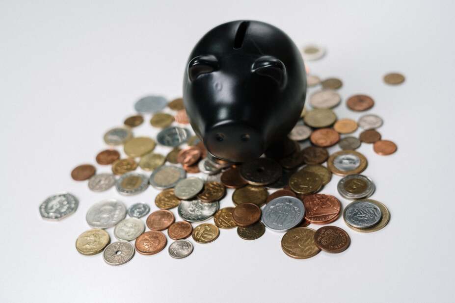 a black, ceramic piggy bank on top of a pile of scattered coins