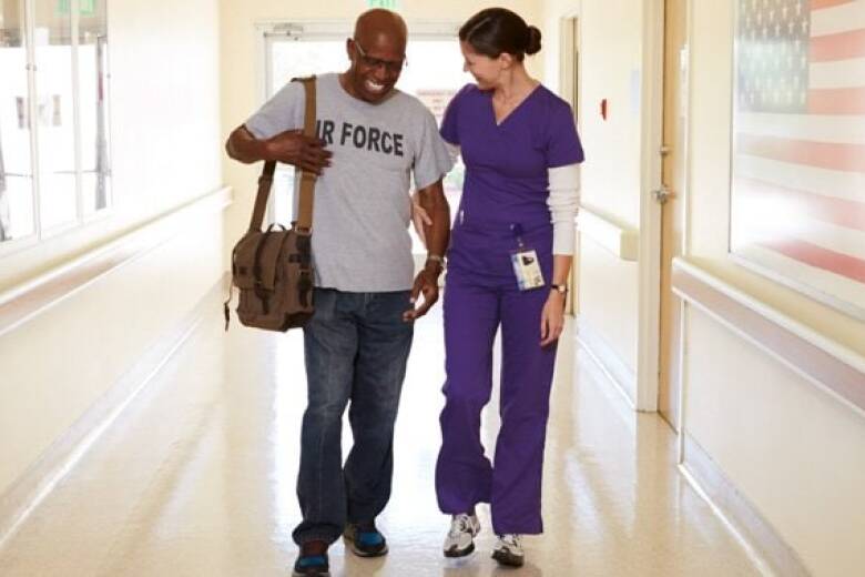 nurse assisting veteran walking down hallway