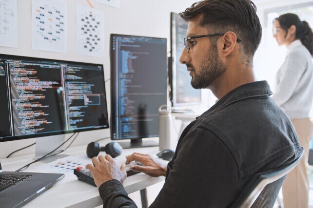 Male and female software developers at their terminals