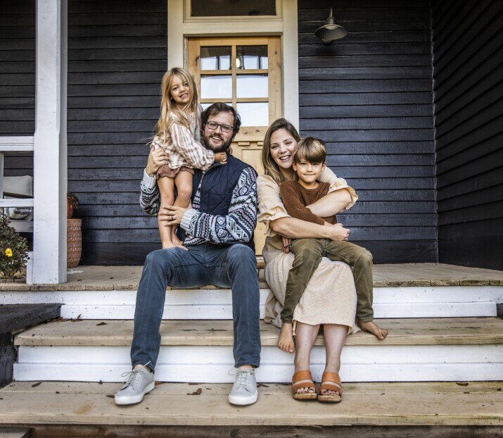 Portrait of young family in front of farmhouse