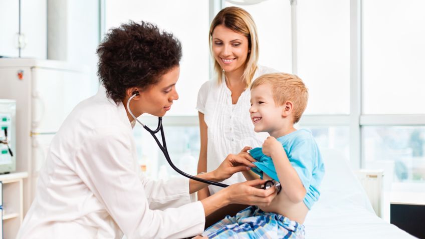 young patient is examined by his doctor while his mom looks on