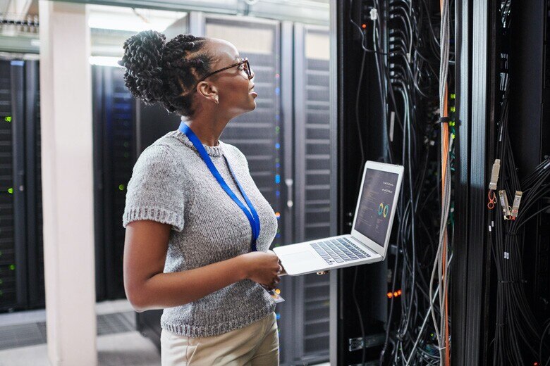network engineer working on her laptop in a server room