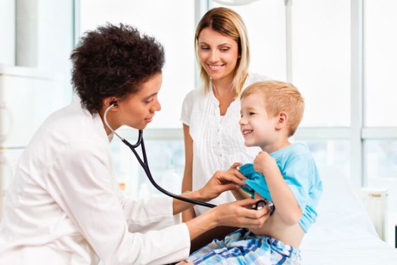 young patient is examined by his doctor while his mom looks on