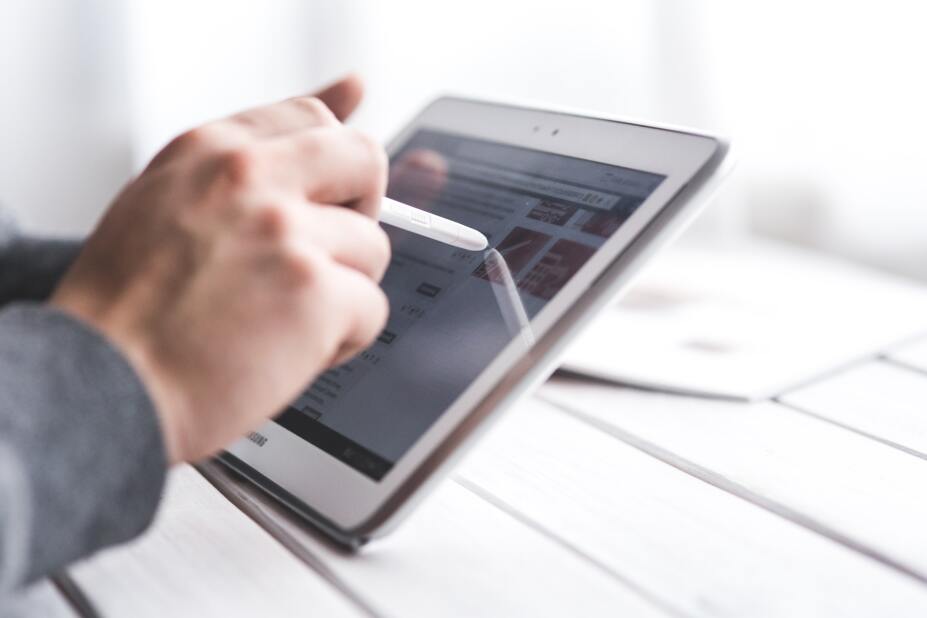 close-up of a hand using a stylus pen to touch the screen of a tablet
