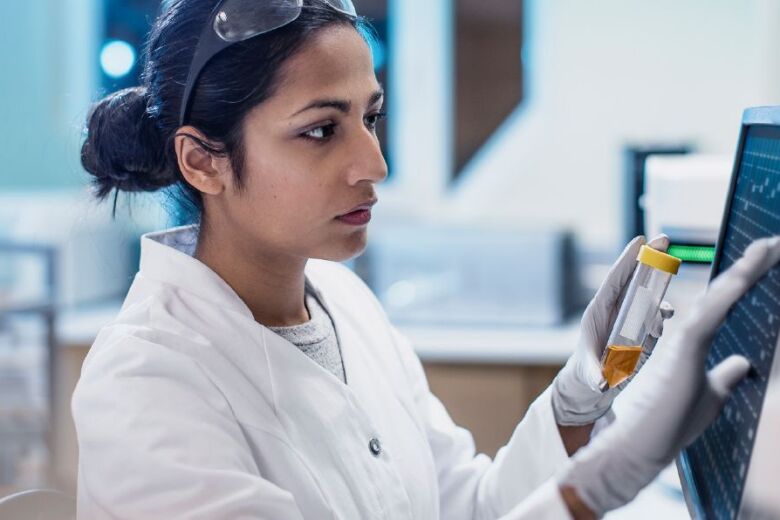 Woman lab tech at monitor with sample container