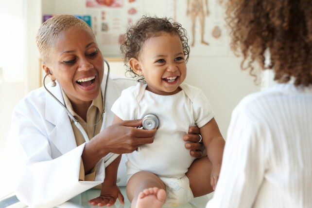 doctor listening to the heart of a smiling toddler patient