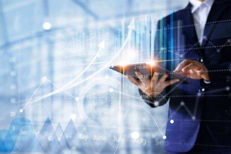 business man holding a tablet under a layer of various transparent graphs