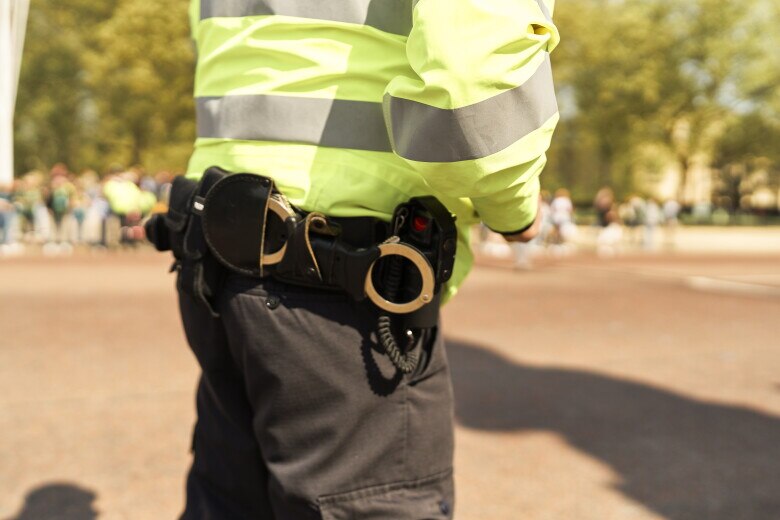 Police officer standing in a public area, providing security and maintaining order while wearing a high visibility jacket and uniform
