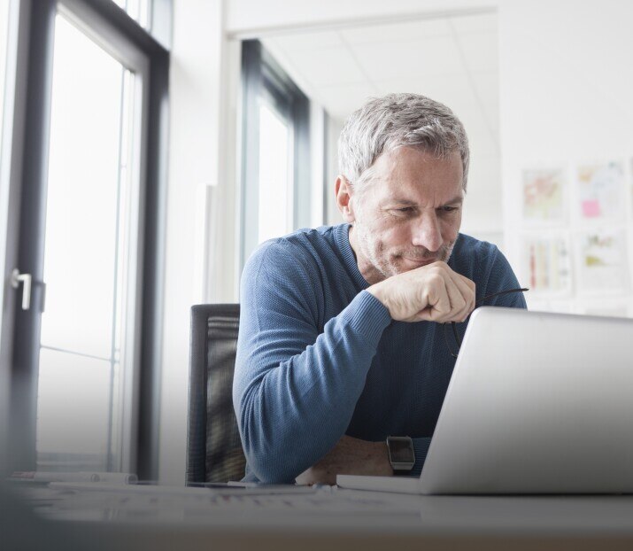 Mature man sitting in office using laptop